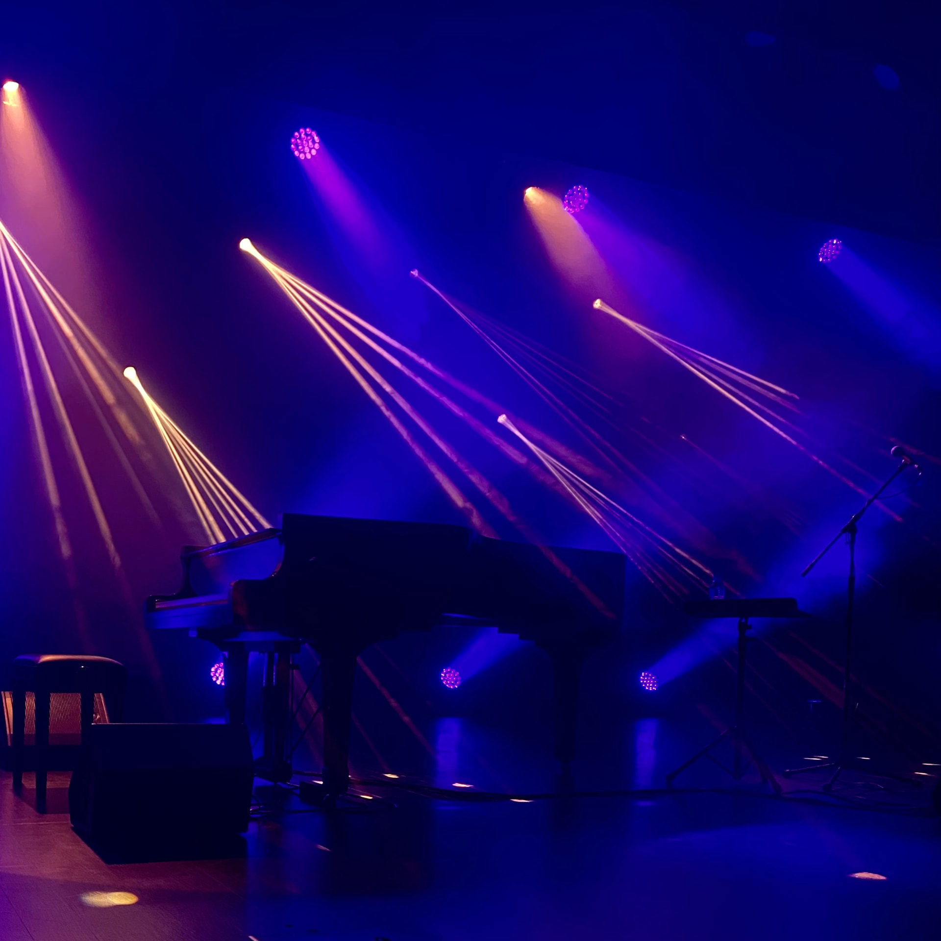 Piano iluminado por feixes de luz num palco escuro